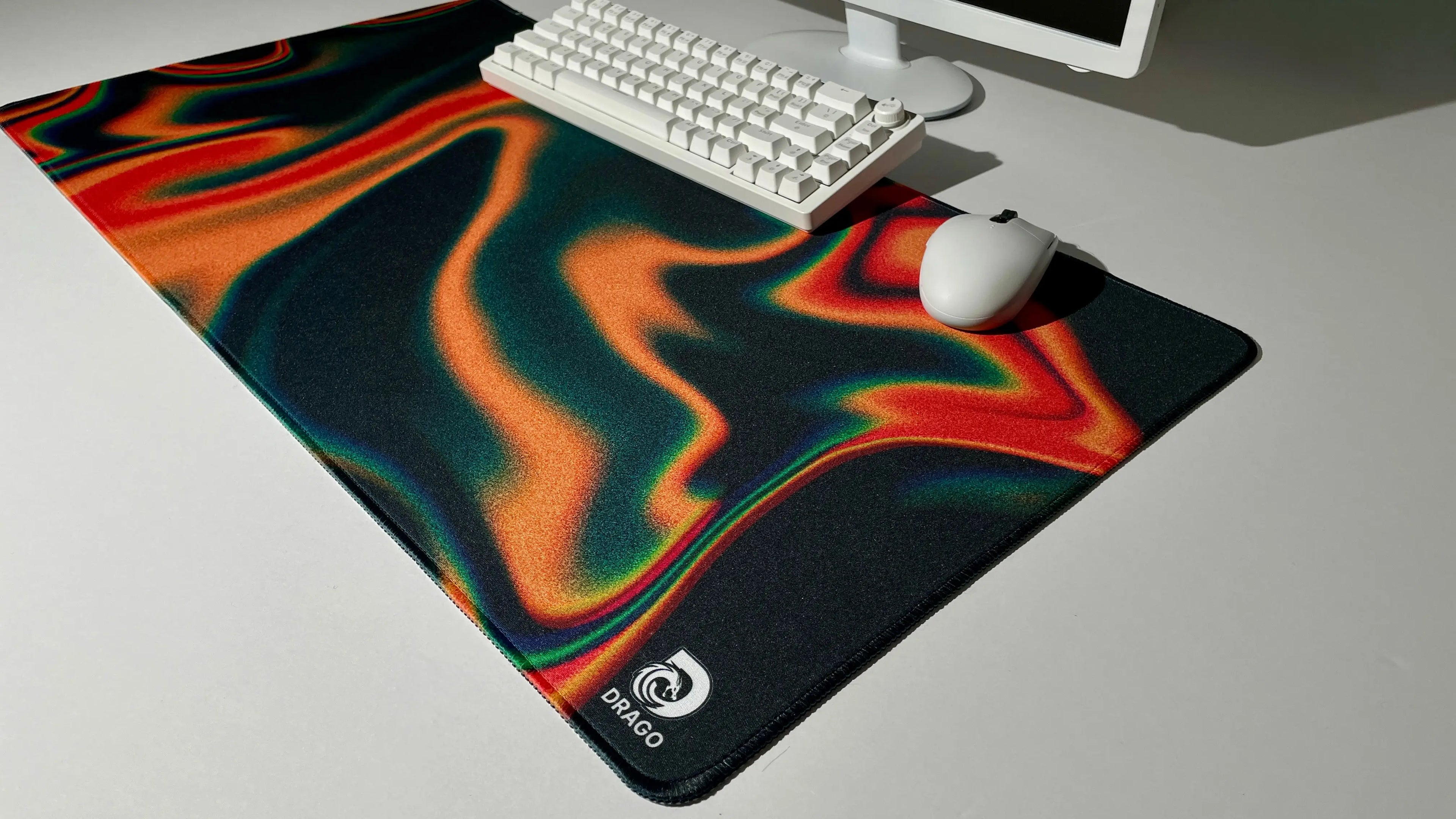 Orange and black mouse pad with a swirling design on a desk with a keyboard and mouse.