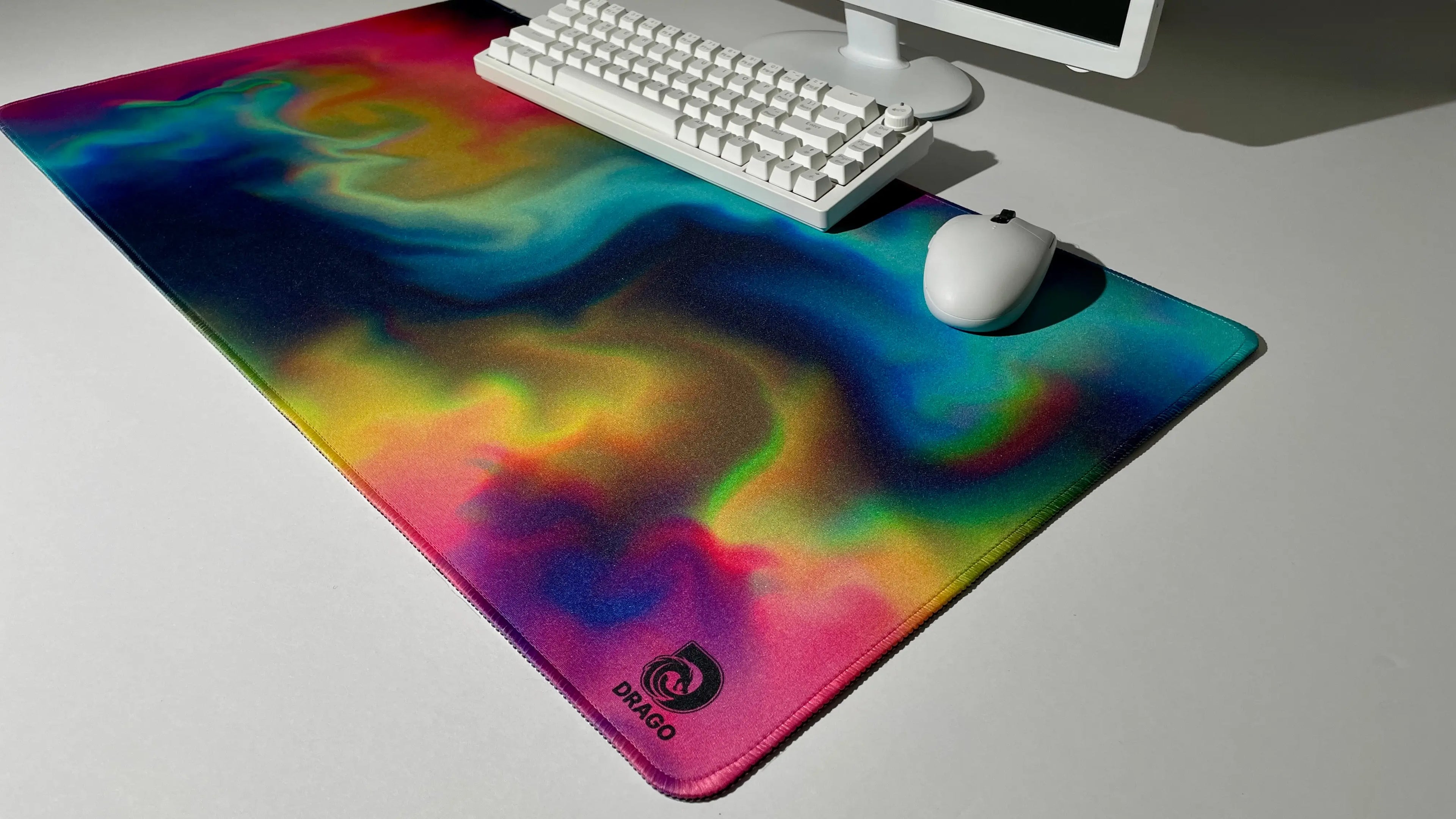 Rainbow mouse pad with a swirling design on a desk with a keyboard and mouse.