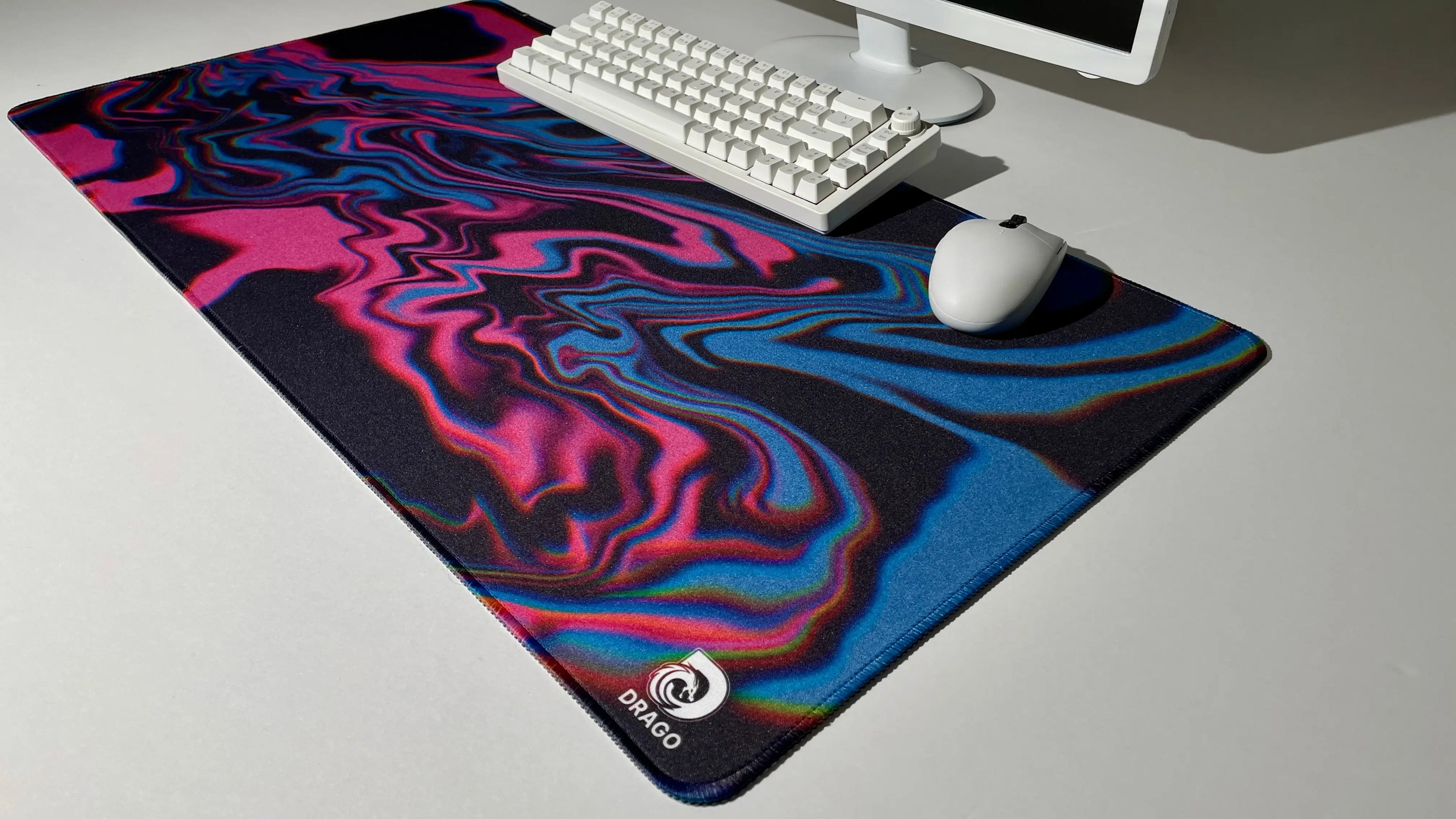 Pink and blue mouse pad with a swirling design on a desk with a keyboard and mouse.